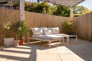 A wooden deck with a sofa and a table, surrounded by a wooden fence and potted plants. - Auld Burn Road (No 2) (St Andrews)