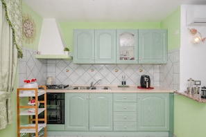 Una cocina con armarios verdes, un fregadero, una estufa y una cafetera.
