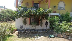 Une maison avec un balcon, un petit jardin et une table avec des chaises.