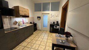 A compact kitchen with a sink, stove, microwave, and a dining area with a table and chairs.