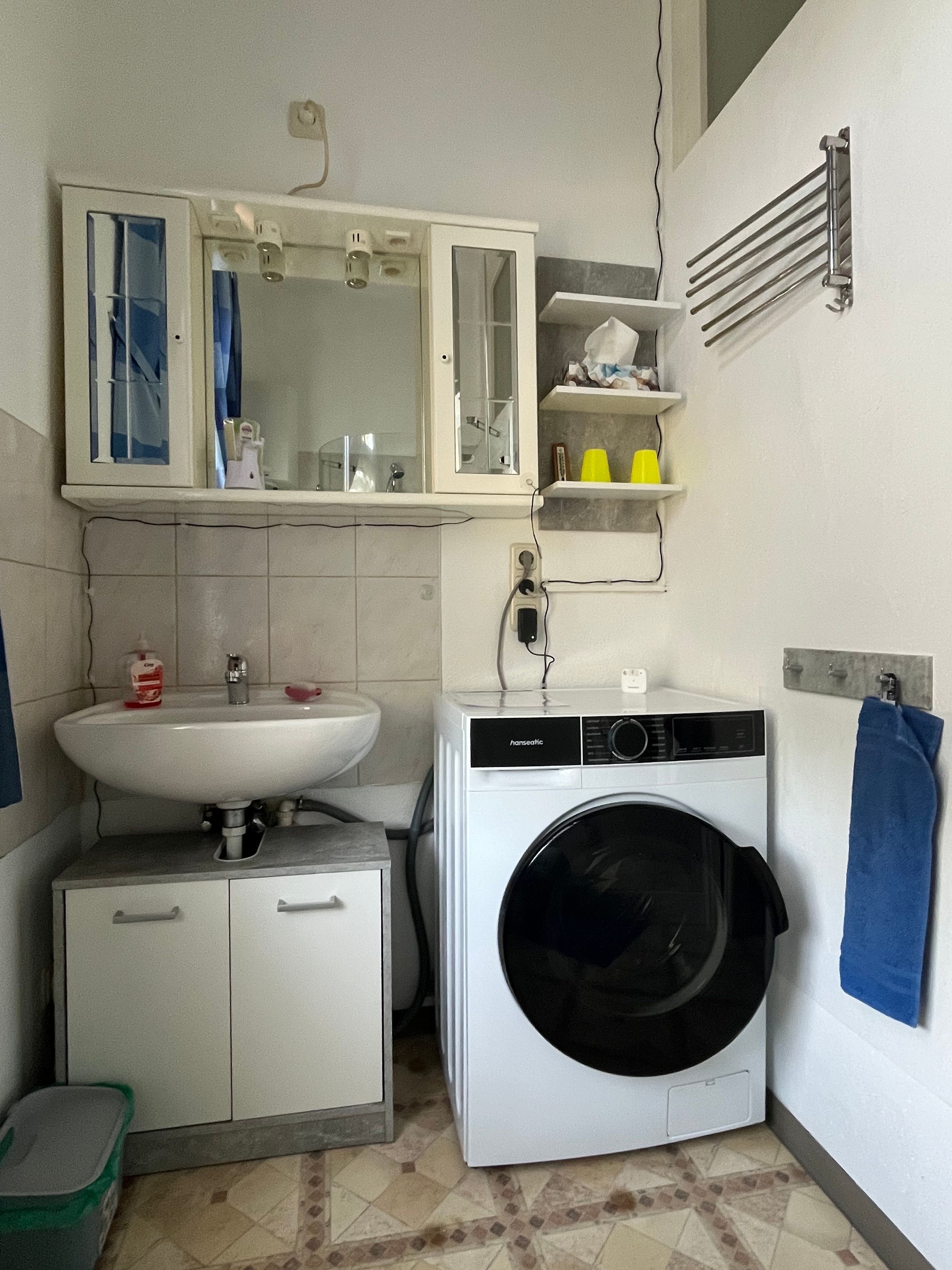 Een kleine badkamer met een wastafel, spiegel en een wasmachine.