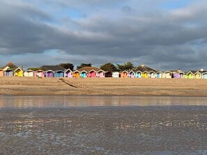 A row of colorful beach huts along a shoreline. - Adorable 2-bedroom bungalow in tranquil Rustington perfect for relaxing (Rustington)