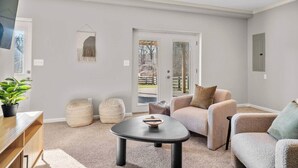 A living room with a sofa, a coffee table, and a TV mounted on the wall. - Clemens House - Relaxing Lexington Home for Long Stays (Lexington)