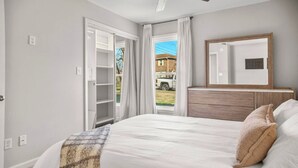 A bedroom with a bed, a dresser, a mirror, and a sliding glass door leading to a patio. - Clemens House - Relaxing Lexington Home for Long Stays (Lexington)