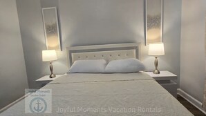 Una cama bien hecha con ropa blanca, dos lámparas de noche y un cabecero.
