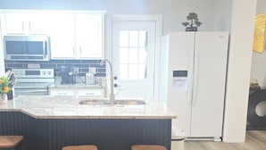 Una cocina moderna con una isla central, electrodomésticos de acero inoxidable y un refrigerador blanco.