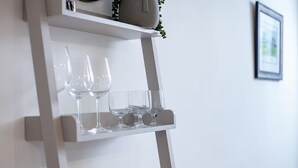 Una estantería blanca con copas de vino y un pequeño adorno.