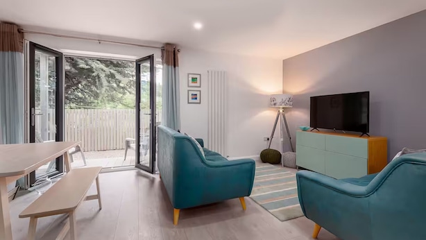 Una sala moderna con un sofá, un televisor y una zona de comedor.