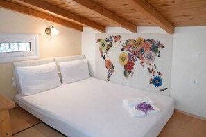 Une chambre à coucher avec un lit, du linge de lit blanc, un plafond en bois, une horloge murale et une fresque florale.