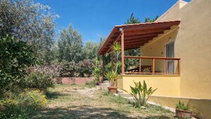 Un edificio giallo con una pergola in legno e un piccolo patio.