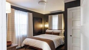 Ein Schlafzimmer mit einem Bett, einem Nachttisch, einer Lampe und einer Tür.