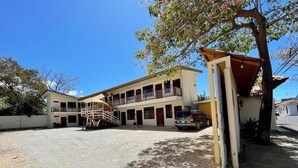 A two-story building with a covered outdoor area and a gravel driveway. - Hotel Wilson Condega (Liberia)