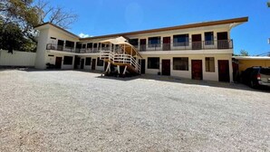 A two-story building with a covered outdoor area and a staircase leading to the upper level. - Hotel Wilson Condega (Liberia)