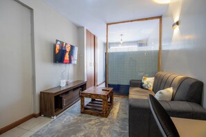 A modern living room with a flat-screen TV, wooden furniture, and a sofa with patterned cushions. - Charming apartment in Nairobi near JKIA/SGR perfect for your next getaway (Nairobi)