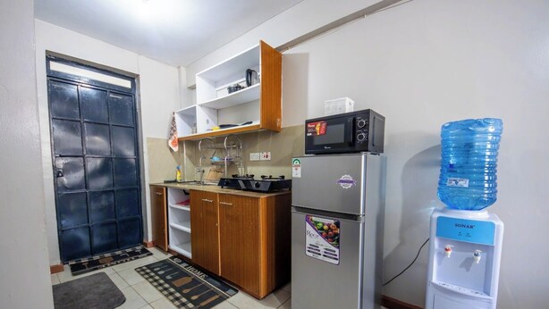 Cocina compacta con refrigerador, microondas y dispensador de agua.