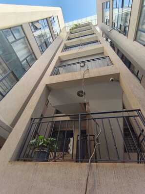 A multi-story building with a modern architectural design, featuring balconies with metal railings and potted plants. - Charming apartment in Nairobi near JKIA/SGR perfect for your next getaway (Nairobi)