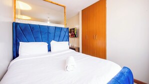 Habitación de hotel con una cama grande, un armario de madera y un espejo en la pared.