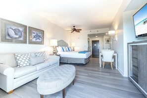 Ein modernes Hotelzimmer mit Bett, Sofa, kleinem Tisch und Fernseher.