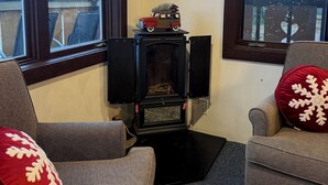 Una sala de estar acogedora con chimenea, dos ventanas y adornos navideños.