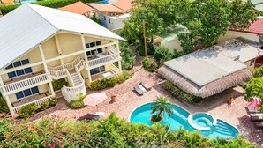 Un área de piscina con una piscina circular, sillas de descanso y una escalera que lleva a un edificio con balcones.