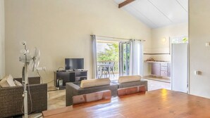 Amplia sala de estar con una mesa de comedor de madera, asientos cómodos, un televisor y vistas al exterior.