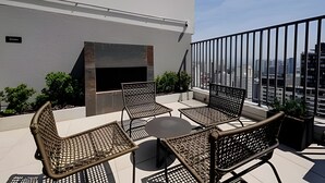 Une terrasse sur le toit dotée d’une cheminée intégrée, de sièges d’extérieur et offrant une vue sur le paysage urbain.