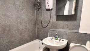 A modern bathroom with a bathtub, sink, and toilet. - Stylish 2-bedroom apartment in peaceful Manchester neighbourhood (Manchester)