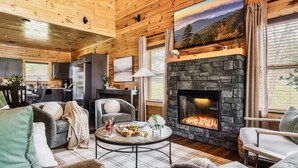 Ein gemütliches Blockhaus-Interieur mit Kamin aus Stein, Holzwänden und einem Essbereich.