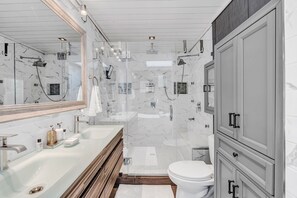 Un baño moderno con ducha envuelta en vidrio, un lavamanos blanco y armarios de madera.