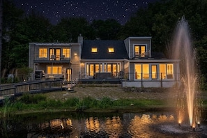 A two-story house with a dock, a fountain, and a pond. -  Oceanfront Seaglass Estate  Near Acadia National Park, with Hot Tub and Views! (Gouldsboro)