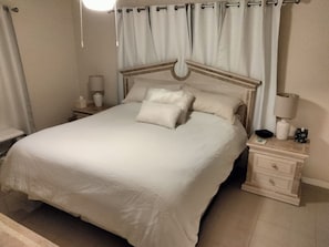 A neatly made bed with a headboard, a bedside table with a lamp, and a nightstand with a lamp. - Citrus Springs Golf & Country Club house / close to Crystal River. (Citrus Springs)