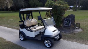 A golf cart parked on a paved path in a park. - Citrus Springs Golf & Country Club house / close to Crystal River. (Citrus Springs)