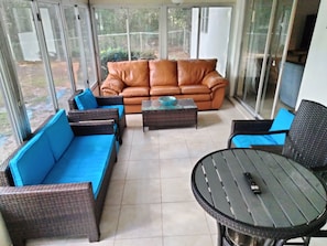 A sunlit room with a brown leather sofa, blue cushioned chairs, a glass coffee table, and a round table with metal legs. - Citrus Springs Golf & Country Club house / close to Crystal River. (Citrus Springs)