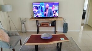 A living room with a television on a wooden stand, a sofa, a coffee table, and decorative items. - Citrus Springs Golf & Country Club house / close to Crystal River. (Citrus Springs)