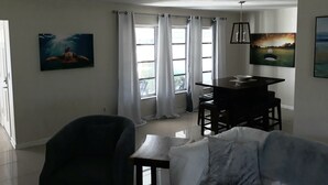 A living room with a ceiling fan, a dining table, a sofa, and two chairs. There are curtains on the windows, and artwork on the walls. - Citrus Springs Golf & Country Club house / close to Crystal River. (Citrus Springs)