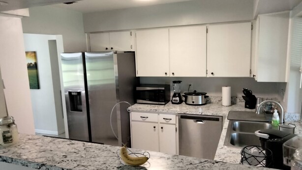 A modern kitchen with white cabinets, stainless steel appliances, a granite countertop, and a banana on the counter. - Citrus Springs Golf & Country Club house / close to Crystal River. (Citrus Springs)