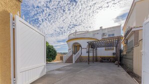 Une courClose agrémentée d’un bâtiment blanc doté d’un balcon circulaire et d’une pergola.