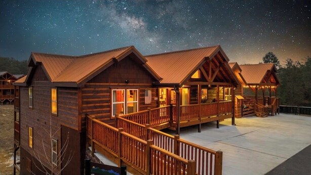 Et hotel i form af en bjælkehytte med flere værelser, et overdækket udendørs område og en stjerneklar nattehimmel.