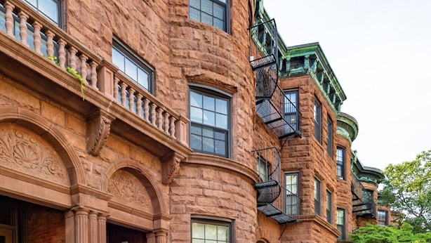 A row of brick townhouses with ornate architectural details, large windows, and a central staircase. - Cozy Loft in South End (Boston)