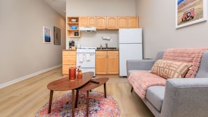 A compact living space with a kitchenette, a sofa, a coffee table, and a rug. - Cozy Loft in South End (Boston)