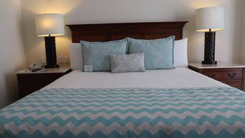 A neatly made bed with a patterned bedspread, two bedside lamps, a wooden headboard, and a nightstand with a phone and a small box.