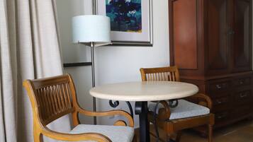 Una habitación con dos sillas de madera, una mesa redonda, una lámpara y un armario.