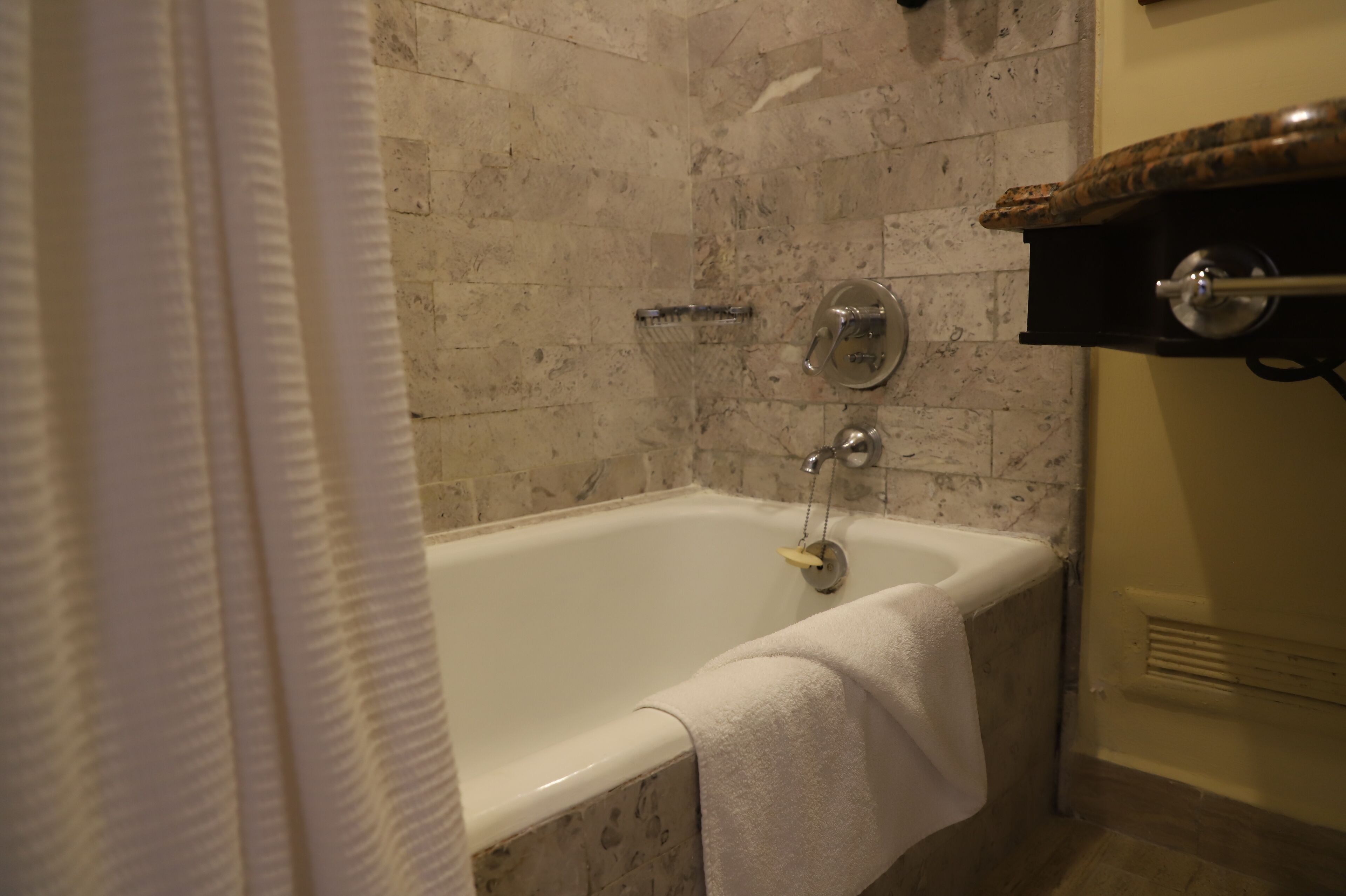 A bathroom with a bathtub, a towel hanging on the side, and a showerhead.