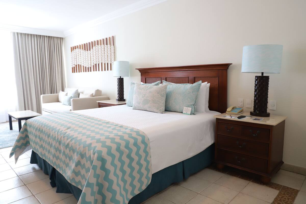 A hotel room with a large bed, two bedside tables, a desk, and a chair.