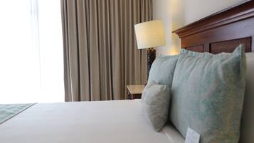 Habitación de hotel con una cama grande, una mesita de noche con lámpara y vistas a las cortinas.