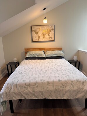 A bedroom with a large bed, a world map on the wall, and two bedside tables with lamps.