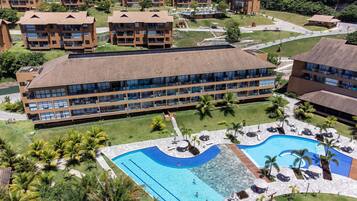 A hotel with multiple buildings, a central swimming pool, and surrounding greenery.
