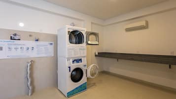 A laundry facility with two washing machines, a drying rack, and a sign with instructions.