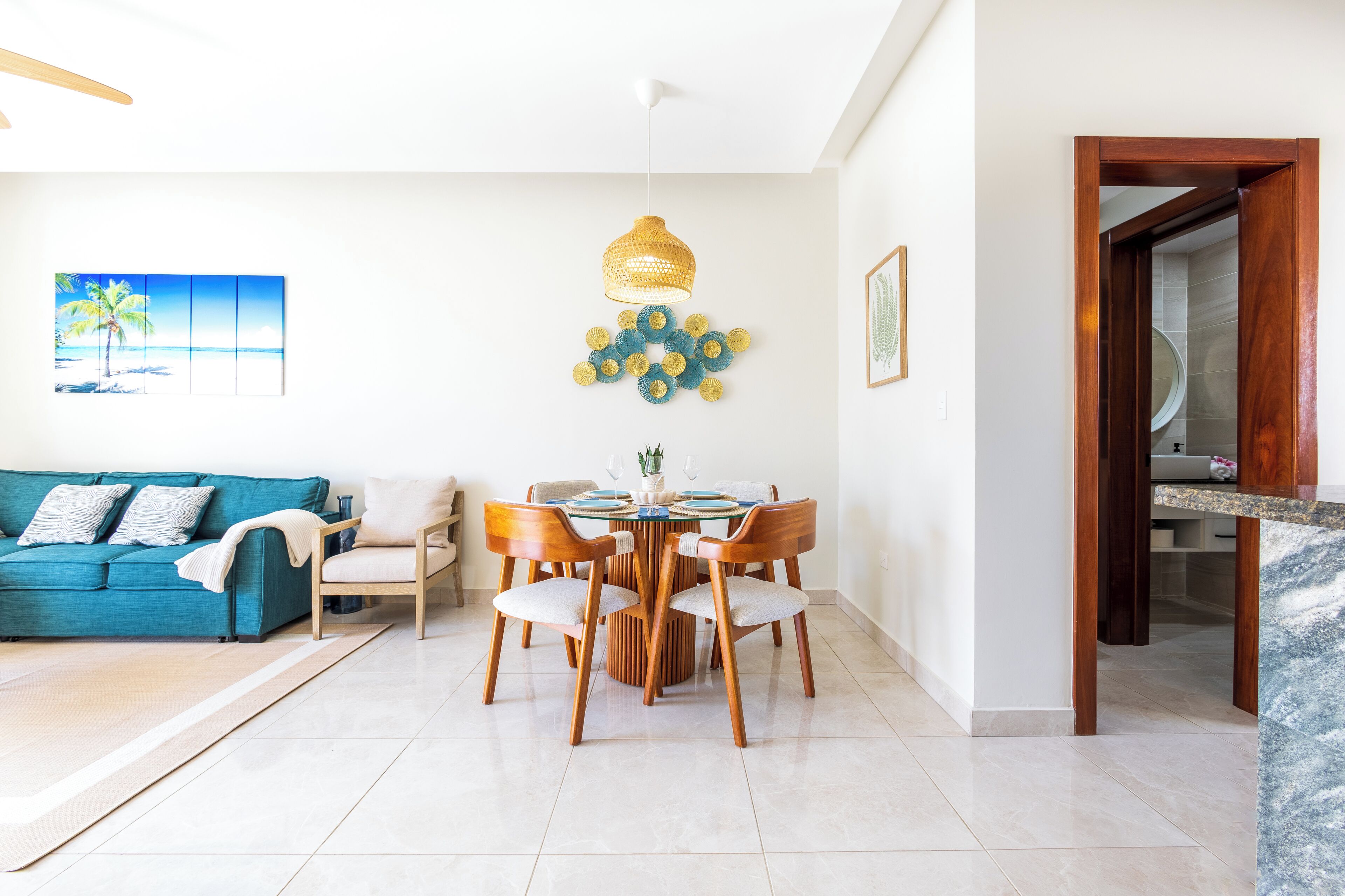 A modern living room with a blue sofa, wooden dining table, and chairs.