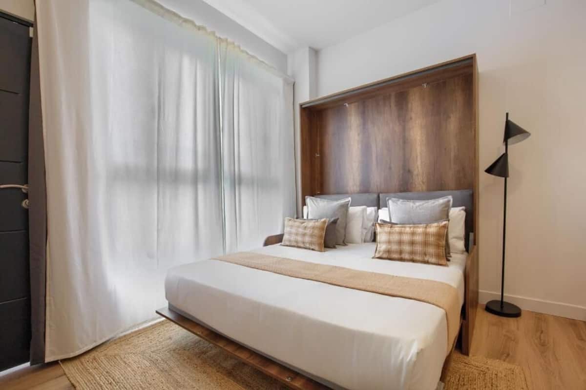 A bedroom with a large bed, a wooden headboard, and a floor lamp.